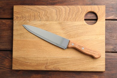 One sharp knife and board on wooden table, top view