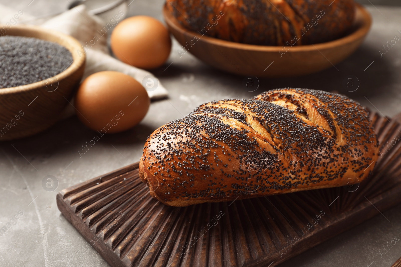 Photo of Board with freshly baked poppy seed roll on table