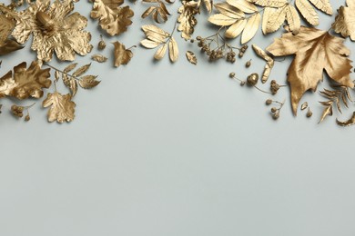 Photo of Beautiful golden leaves, berries and acorns on light grey background, flat lay with space for text. Autumn decor