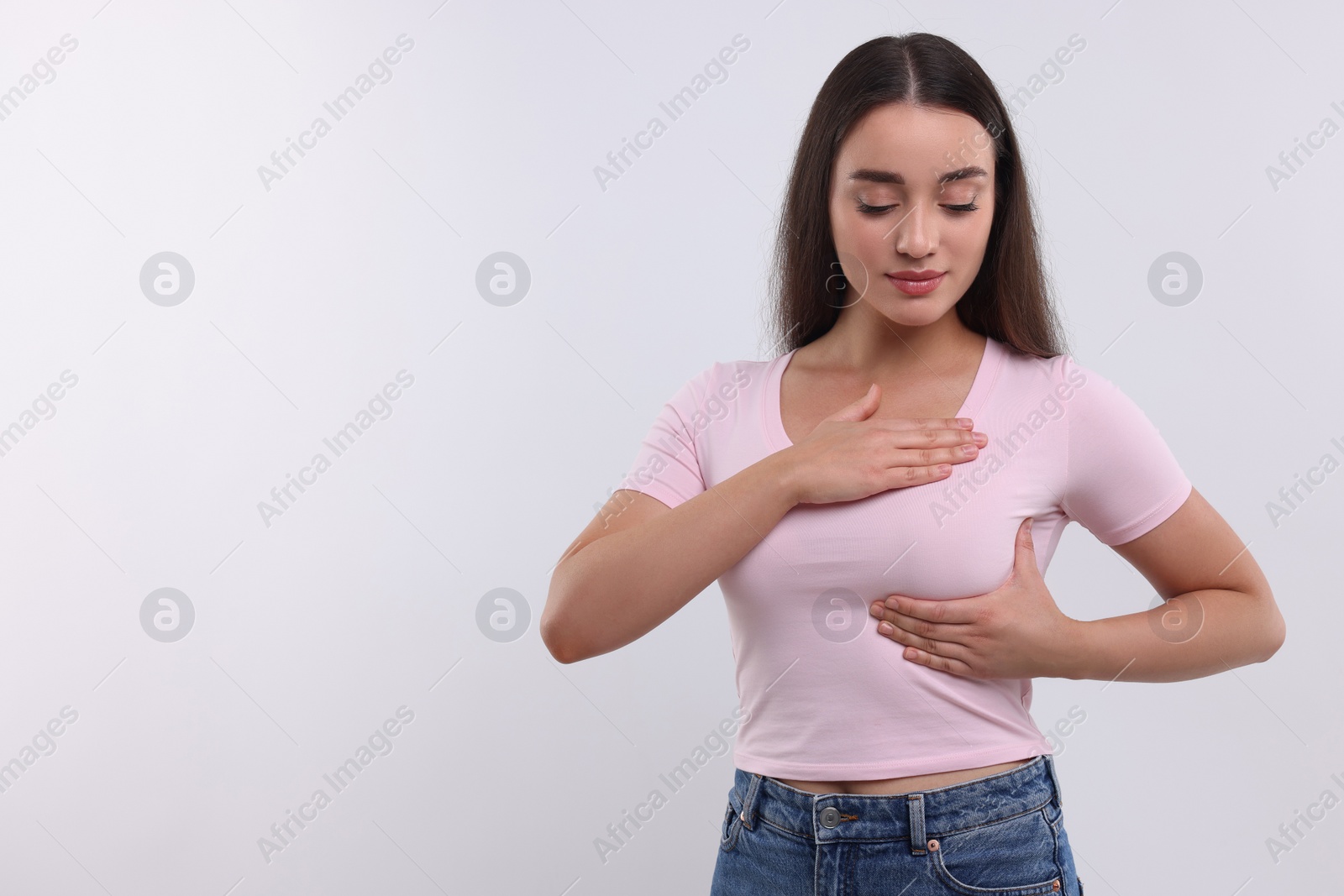 Photo of Beautiful young woman doing breast self-examination on white background, space for text