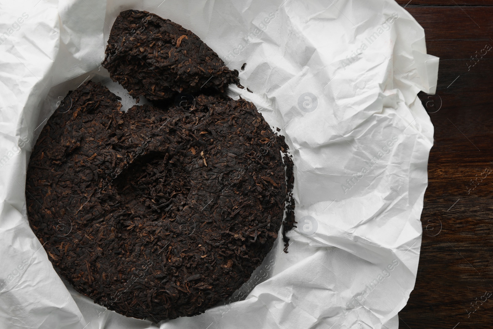 Photo of Broken disc shaped pu-erh tea on wooden table, top view