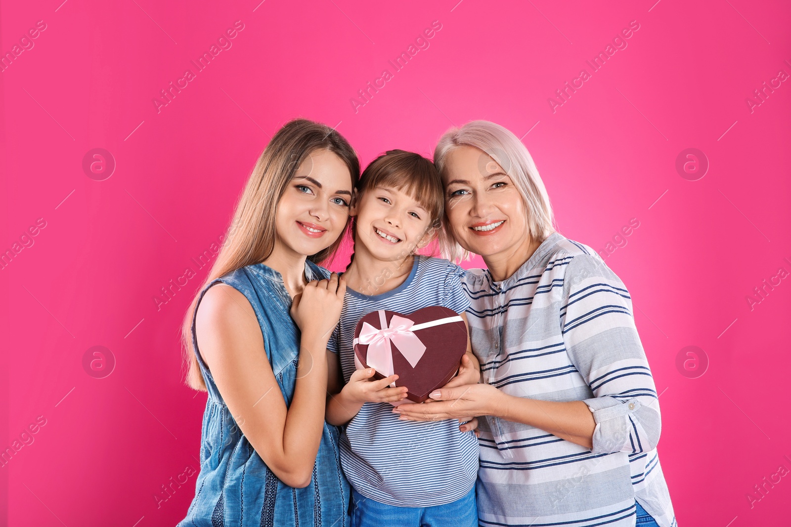 Photo of Beautiful mature lady, daughter and grandchild with gift box on color background. Happy Women's Day