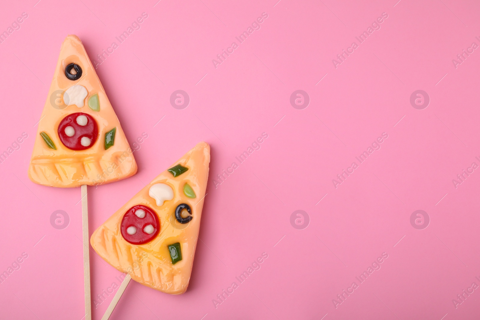 Photo of Pizza shaped lollipops on pink background, flat lay. Space for text