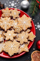 Tasty Christmas cookies, fir branches and festive decor on black table, flat lay