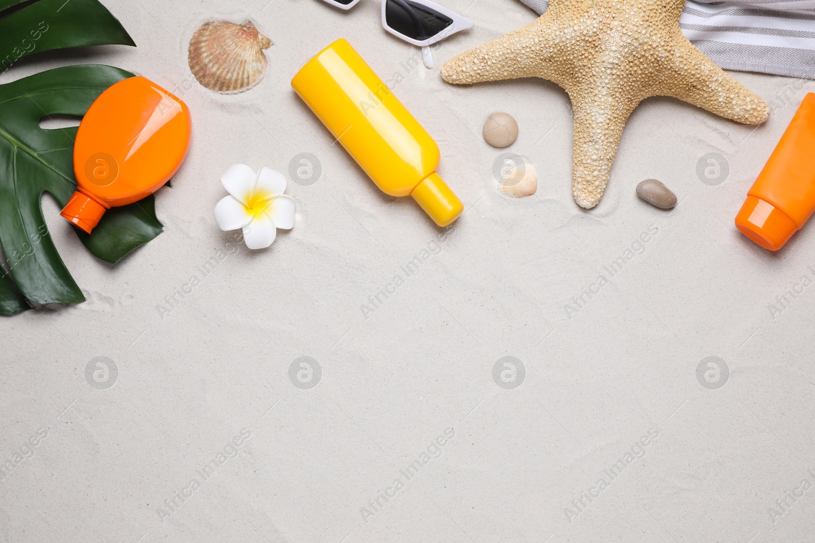 Photo of Flat lay composition with sun protection products on sand. Space for text