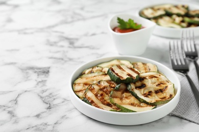 Photo of Grilled zucchini slices served on white marble table. Space for text