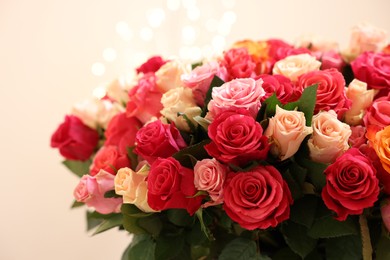 Beautiful bouquet of colorful roses on beige background, closeup