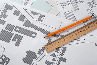 Pencil and ruler on cadastral maps of territory with buildings, flat lay