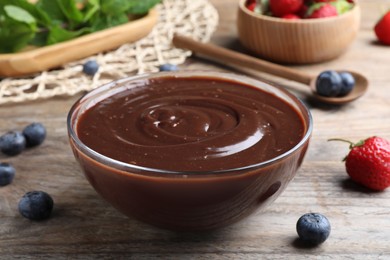 Photo of Delicious chocolate cream and berries on wooden table