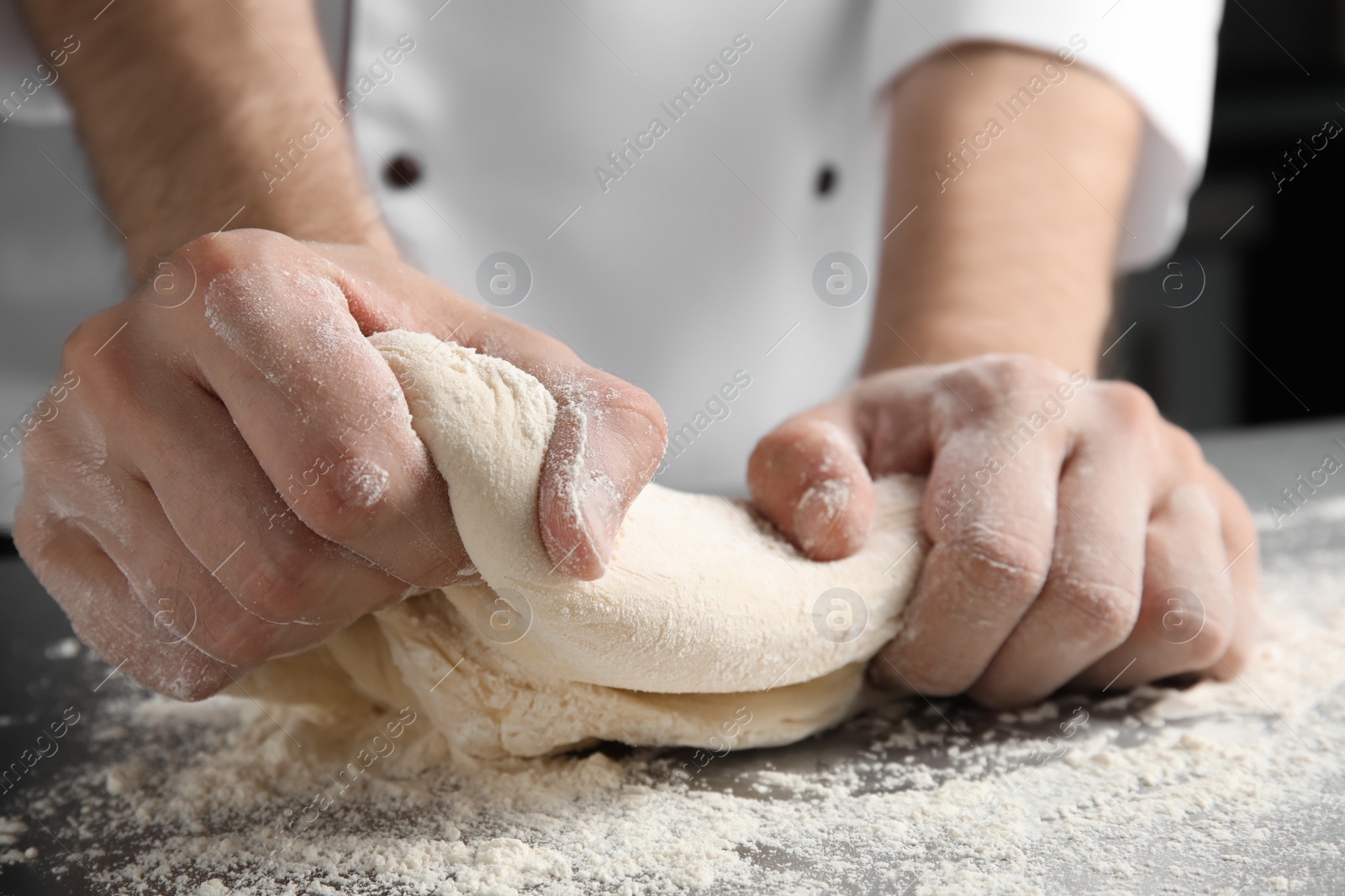 Photo of Man kneading dough for pastry on table