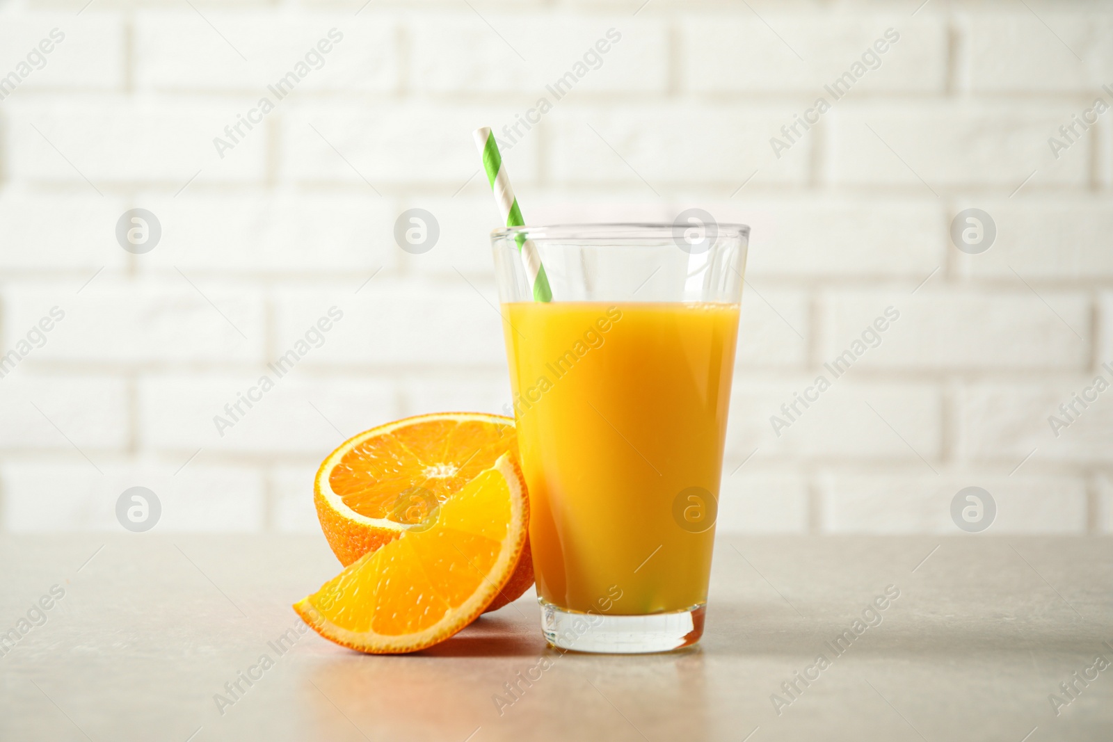 Photo of Glass of orange juice and fresh fruits on light table