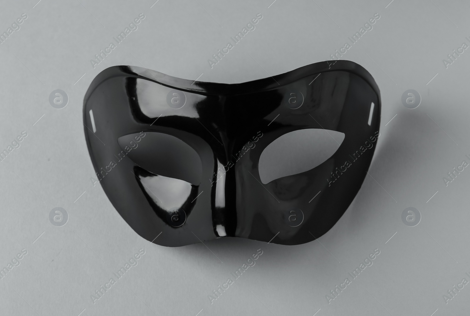 Photo of Black theatre mask on grey background, above view