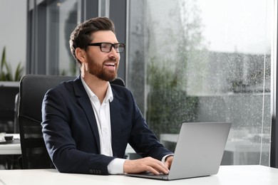 Photo of Man working on laptop at white desk in office. Space for text