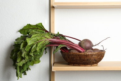 Raw ripe beets in wicker bowl on shelf indoors