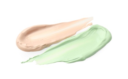 Photo of Strokes of pink and green color correcting concealers isolated on white