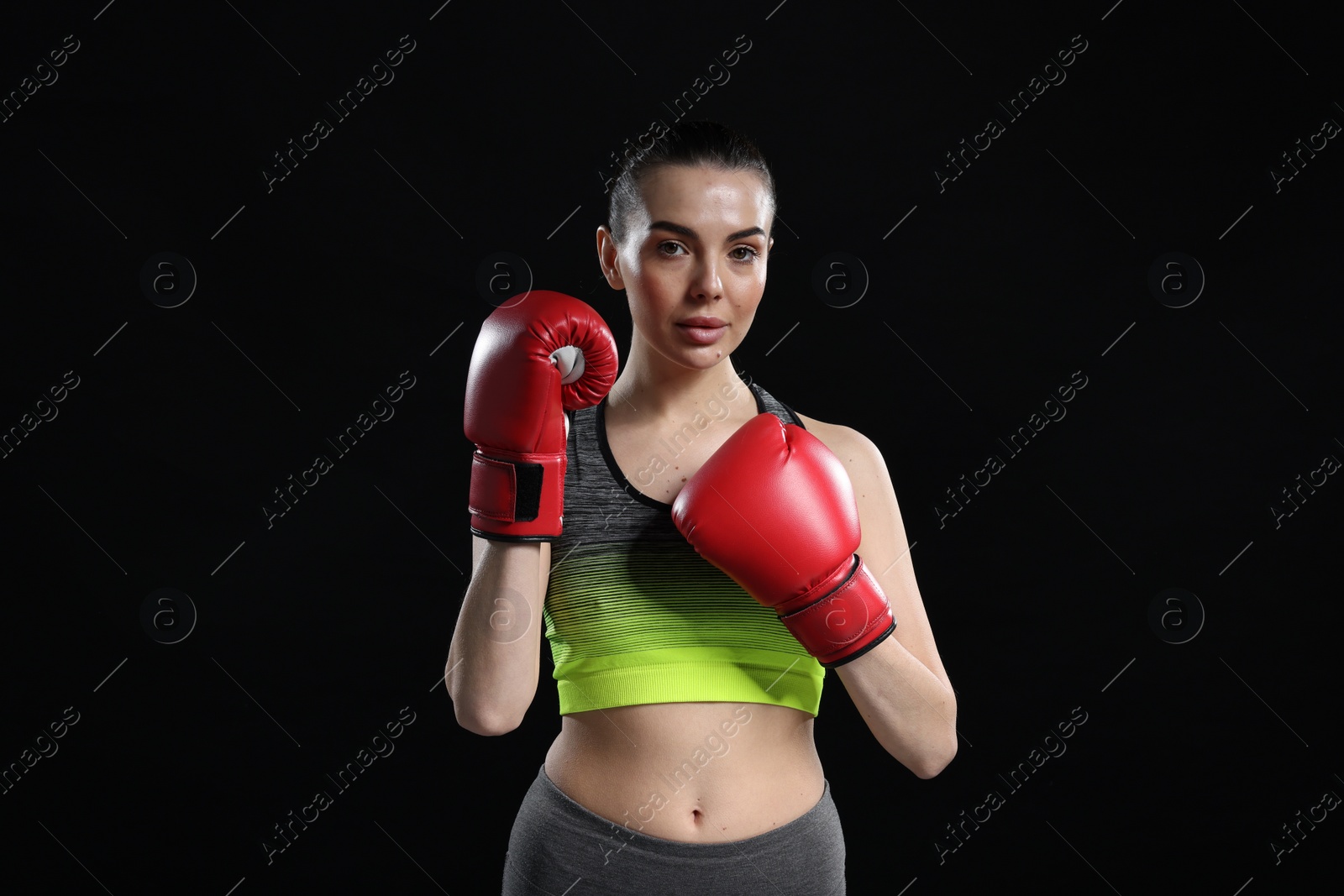 Photo of Portrait of beautiful woman in boxing gloves on black background