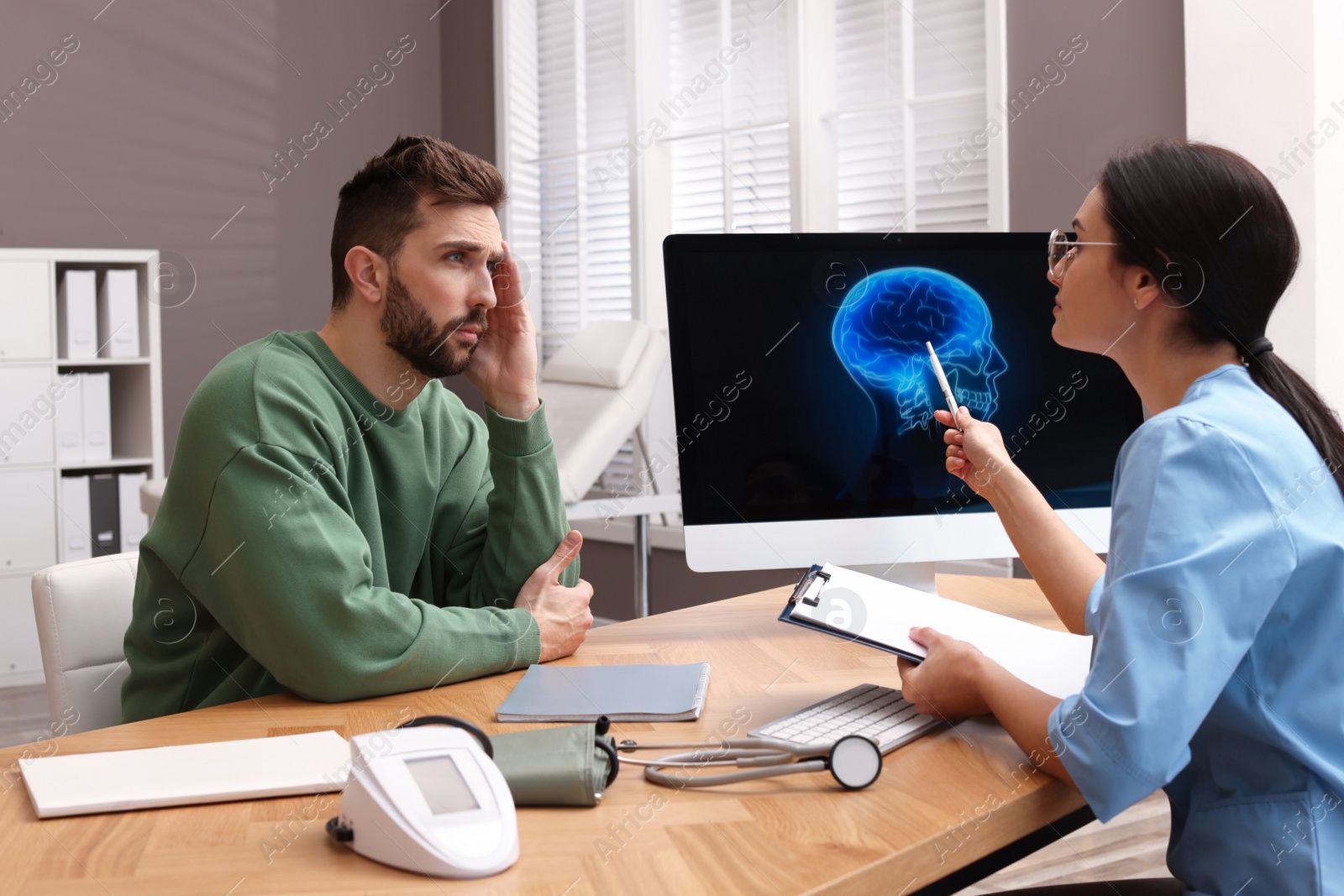 Photo of Neurologist consulting patient at table in clinic