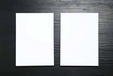 Blank paper sheets for brochure on black wooden background, flat lay. Mock up