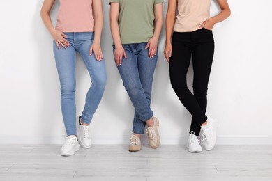 Photo of Women in stylish jeans near white wall, closeup