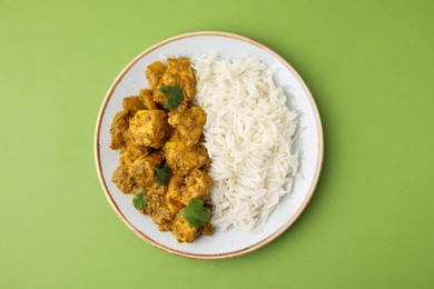 Photo of Delicious chicken curry with rice on green background, top view