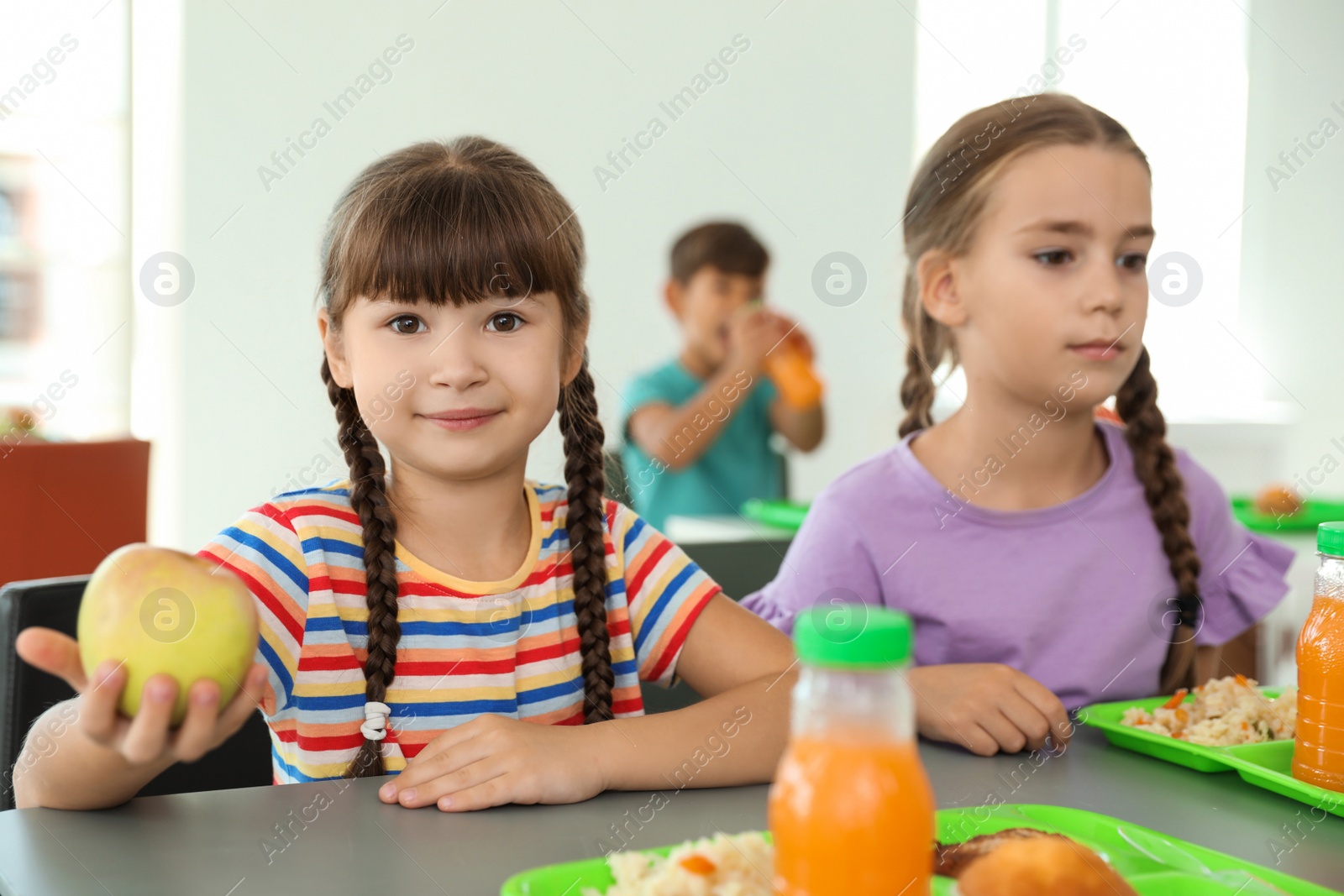 Photo of Children sitting at table and eating healthy food during break at school