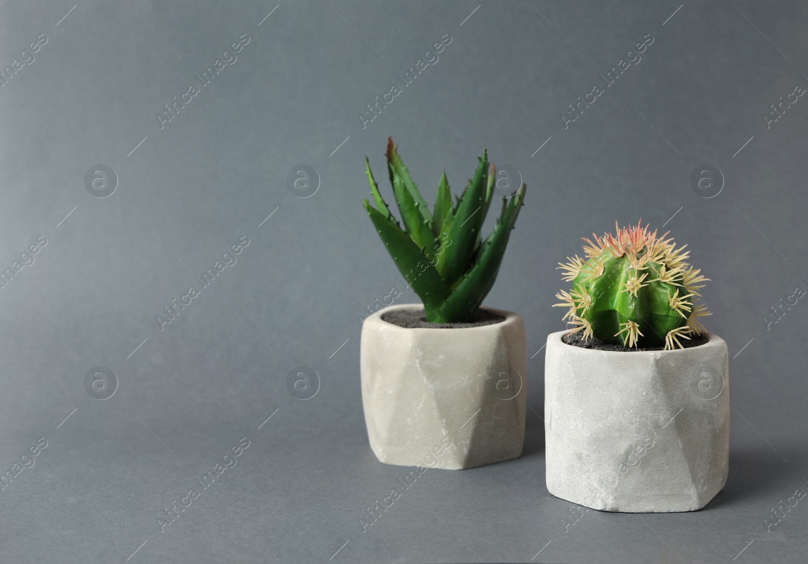 Photo of Beautiful artificial plants in flower pots on grey background, space for text