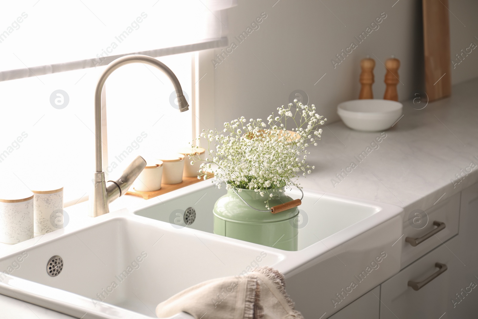 Photo of Bouquet of gypsophila flowers in sink. Kitchen interior design