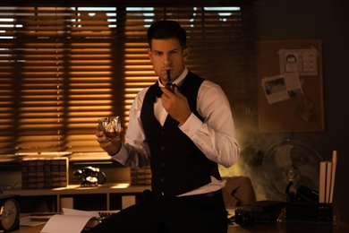 Photo of Old fashioned detective with drink and smoking pipe in office