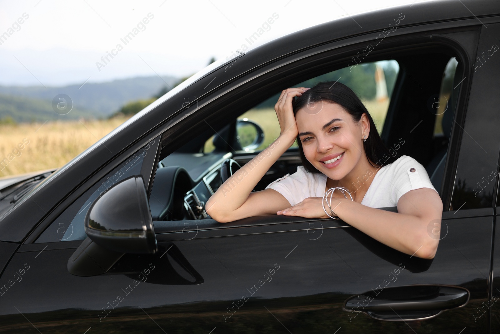 Photo of Enjoying trip. Portrait of beautiful happy woman in car, view from outside