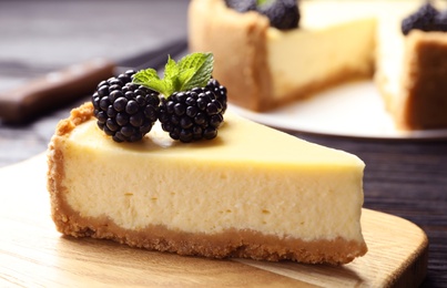 Piece of delicious cheesecake decorated with blackberries on table