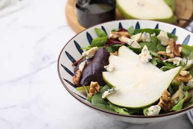 Delicious pear salad in bowl on white marble table, closeup. Space for text