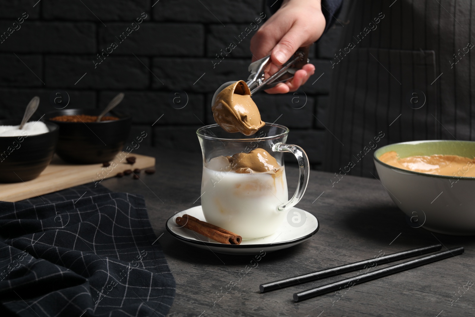 Photo of Woman making dalgona coffee at grey table, closeup