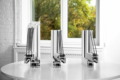 Photo of Samples of modern window profiles on table indoors. Installation service