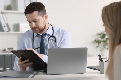 Professional doctor working with patient at white table in hospital