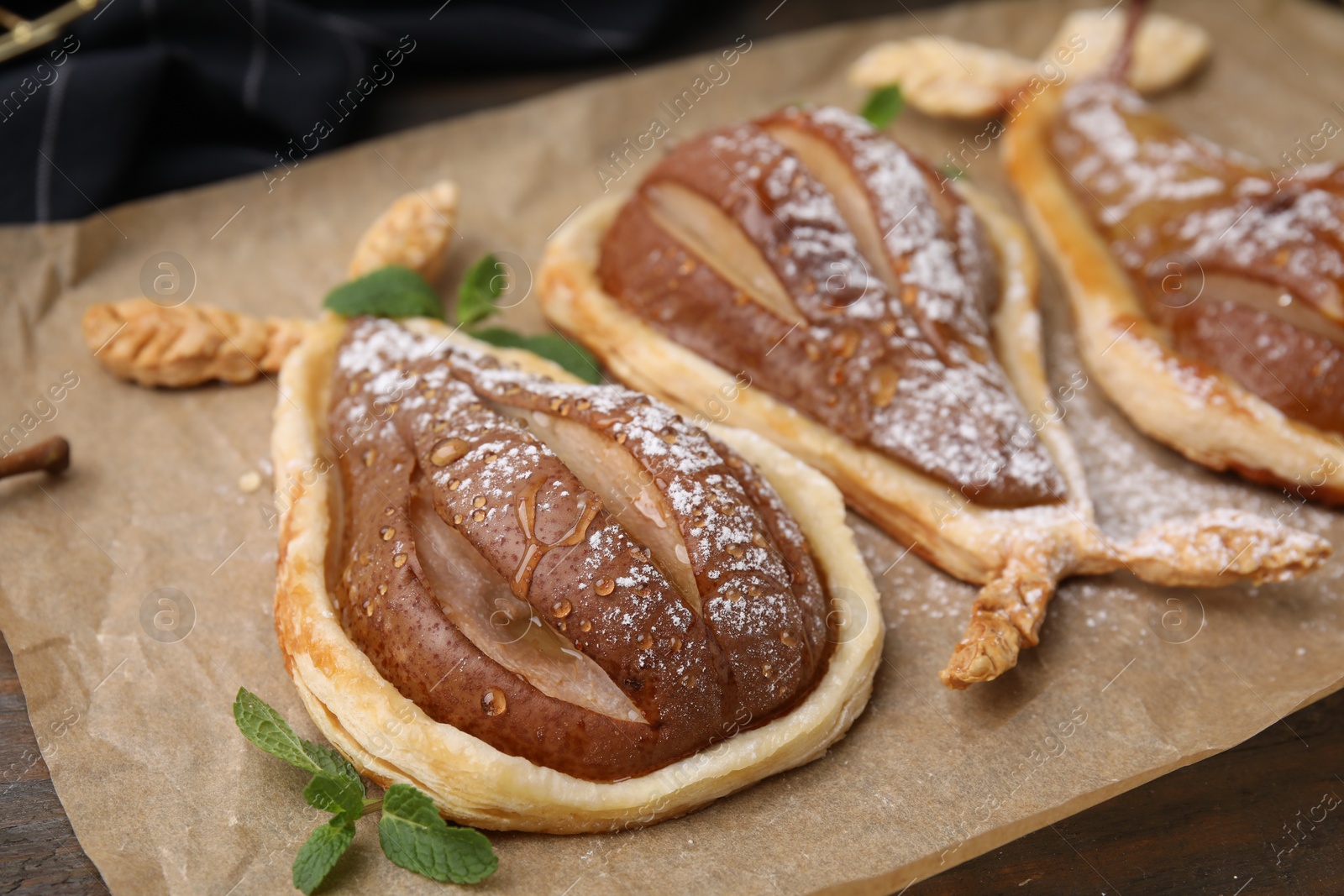 Photo of Delicious pears baked in puff pastry with powdered sugar and mint on table, closeup