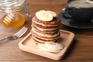 Photo of Plate of banana pancakes served on wooden table, closeup