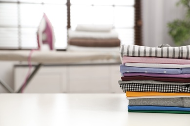 Folded clean clothes on table indoors, space for text. Laundry day