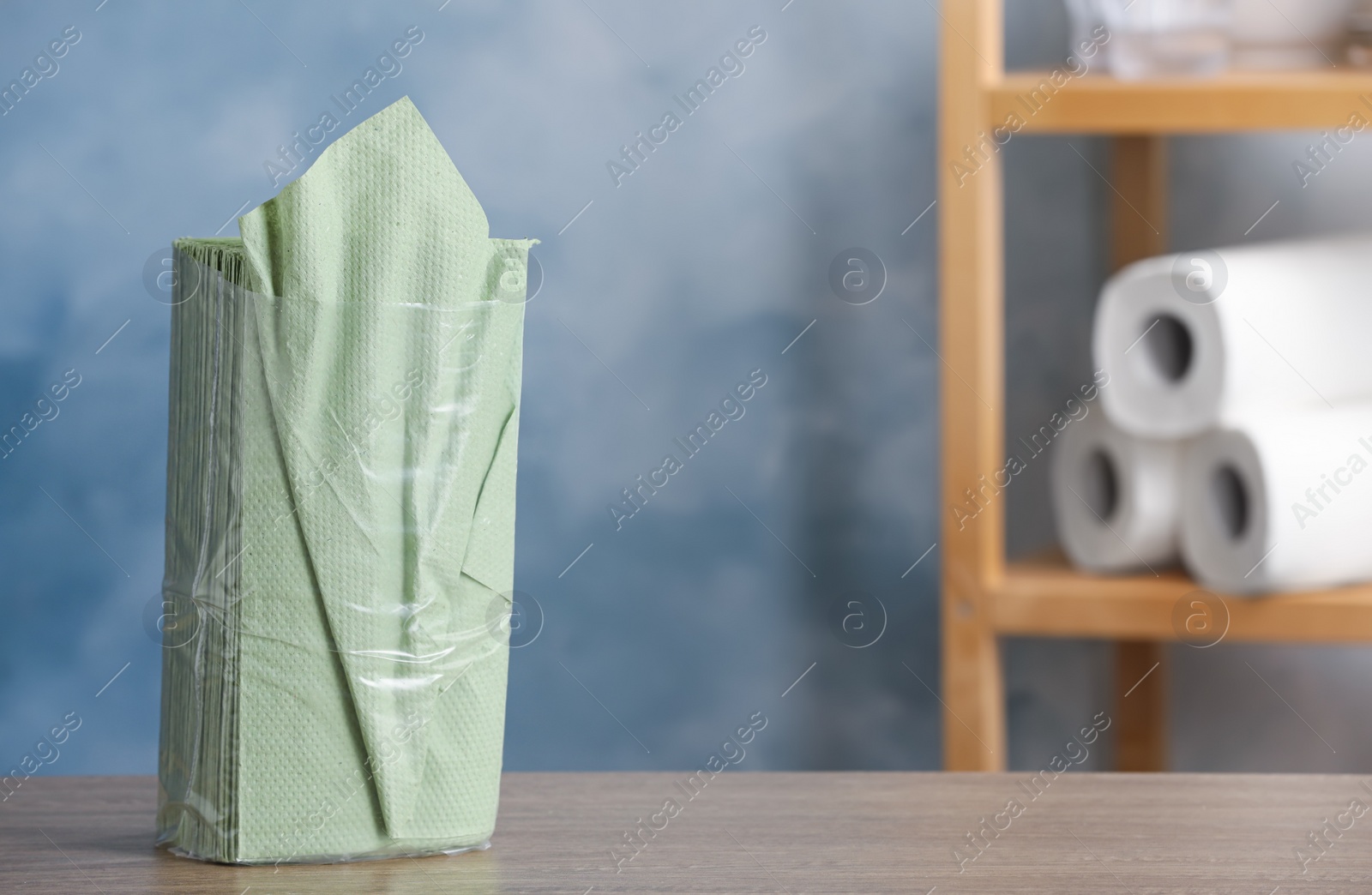 Photo of Green paper napkins on wooden table indoors. Space for text