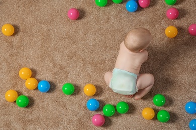 Cute little baby crawling on carpet with toys, top view