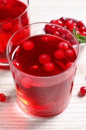 Tasty cranberry juice in glasses and fresh berries on white wooden table, closeup