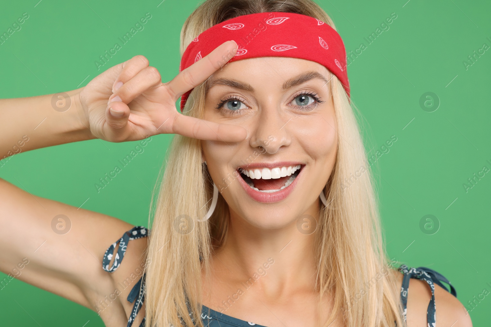 Photo of Portrait of happy hippie woman showing peace sign on green background