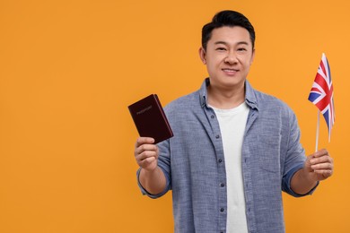 Immigration. Happy man with passport and flag of United Kingdom on orange background, space for text
