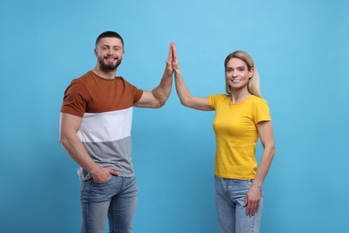 Happy couple giving high five on light blue background