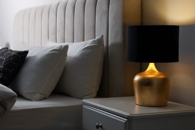 Photo of Stylish lamp on bedside table indoors. Bedroom interior element