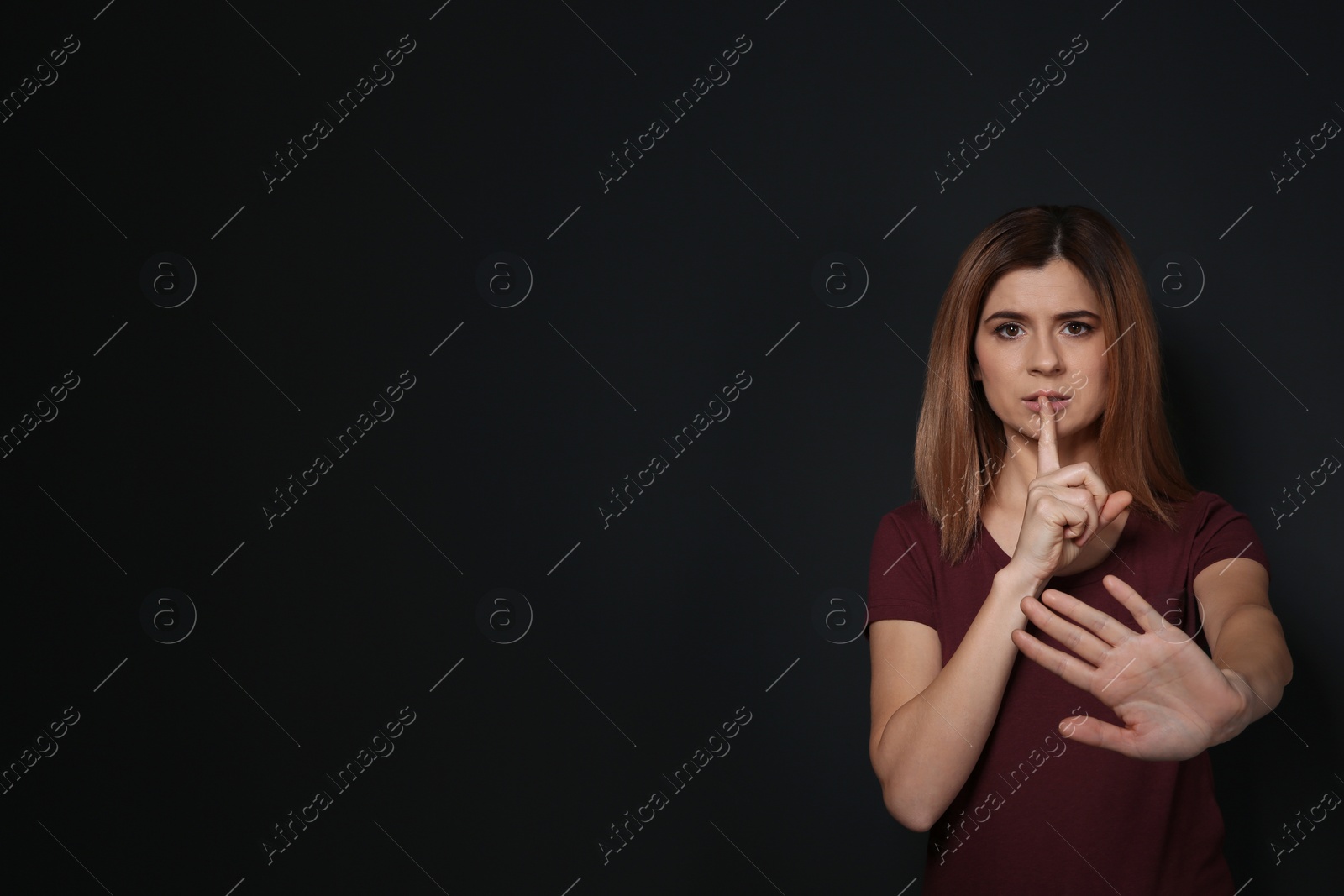 Photo of Woman showing HUSH gesture in sign language on black background, space for text