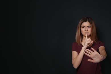 Photo of Woman showing HUSH gesture in sign language on black background, space for text
