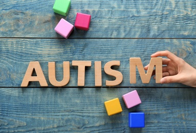 Photo of Woman and word AUTISM made with letters on wooden background