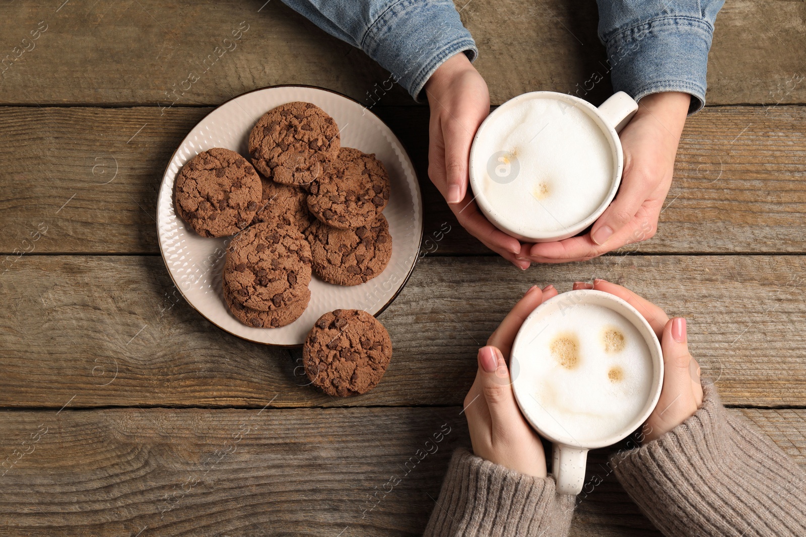 Photo of Women having coffee break at wooden table, top view