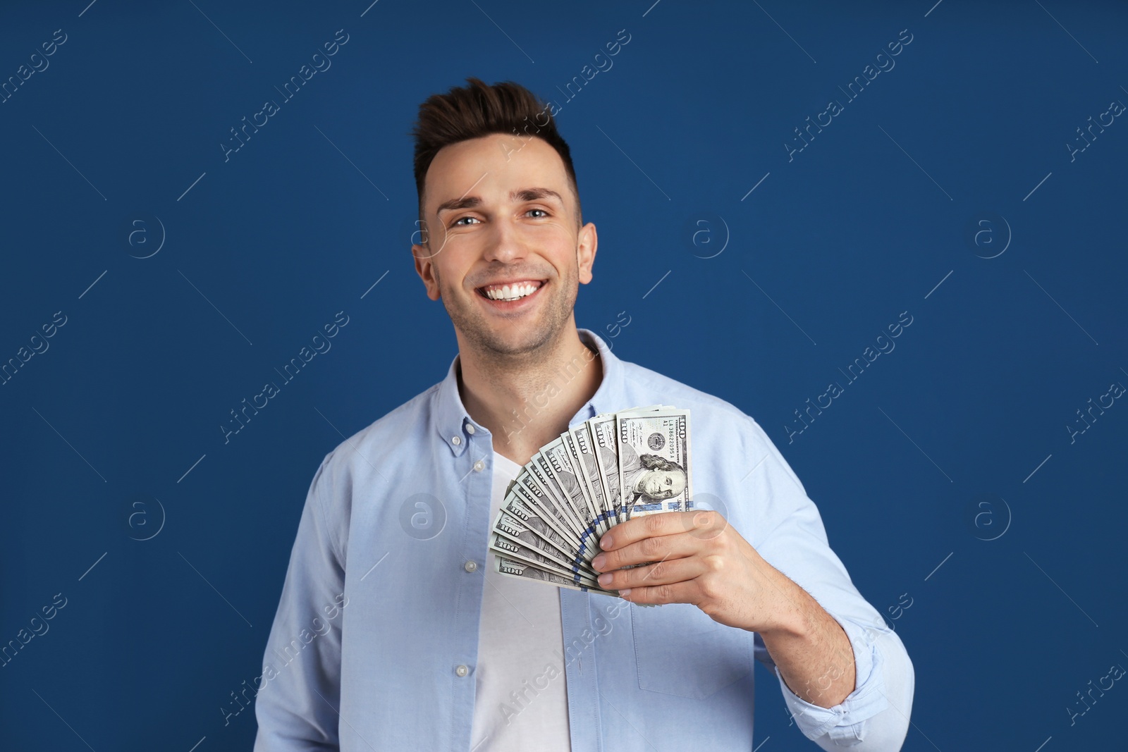 Photo of Happy man with cash money on blue background