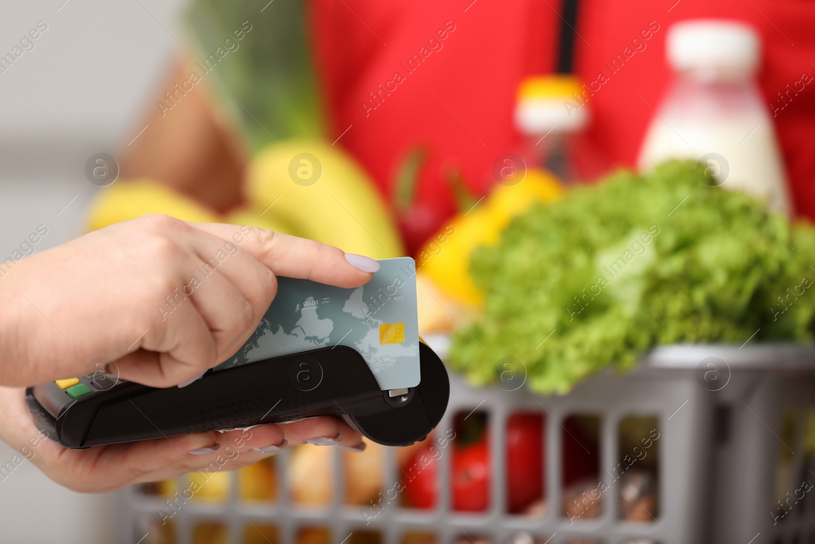 Photo of Customer using bank terminal to pay for food delivery indoors, closeup